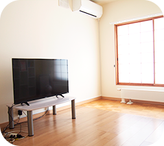 テレビとエアコンのある大きな窓の部屋の写真